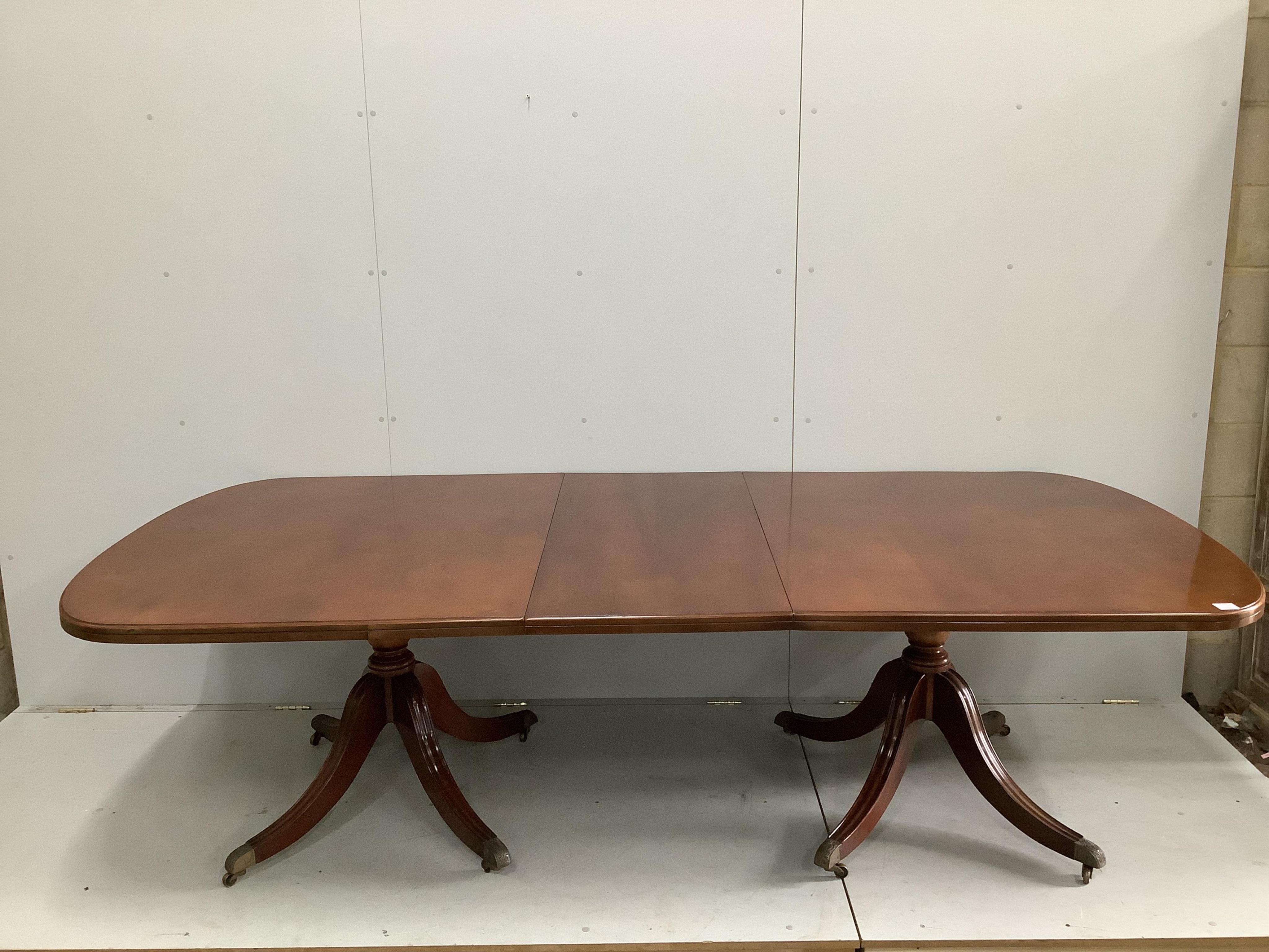 A reproduction George III style mahogany twin pillar extending dining table, 264cm extended, one spare leaf, width 121cm, height 73cm. Condition - good